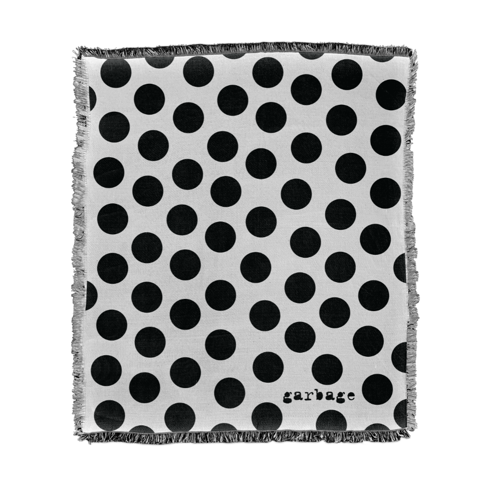 Polka dot patterned blanket or throw with frayed edges and the word ’garbage’ printed in the corner.