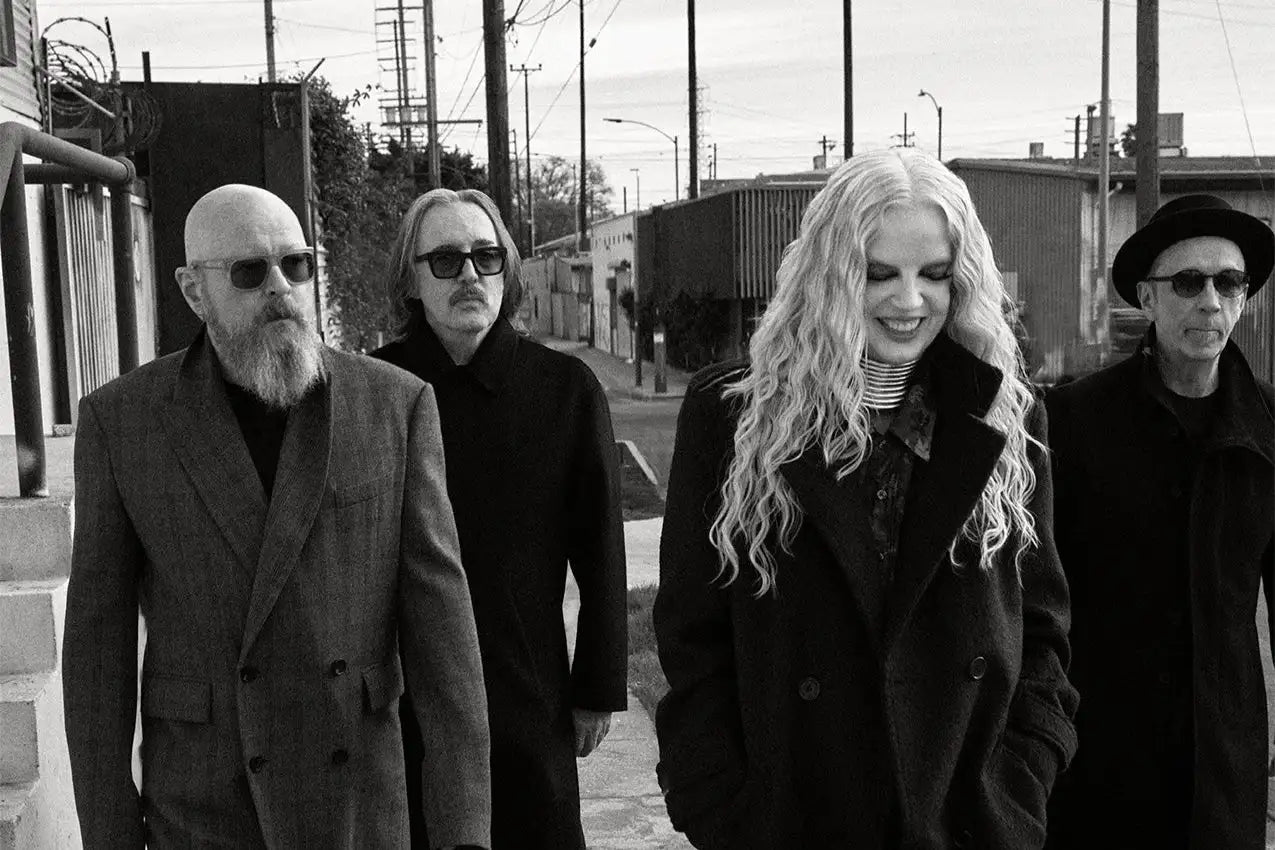 Black-and-white photograph of four individuals walking down an urban street.