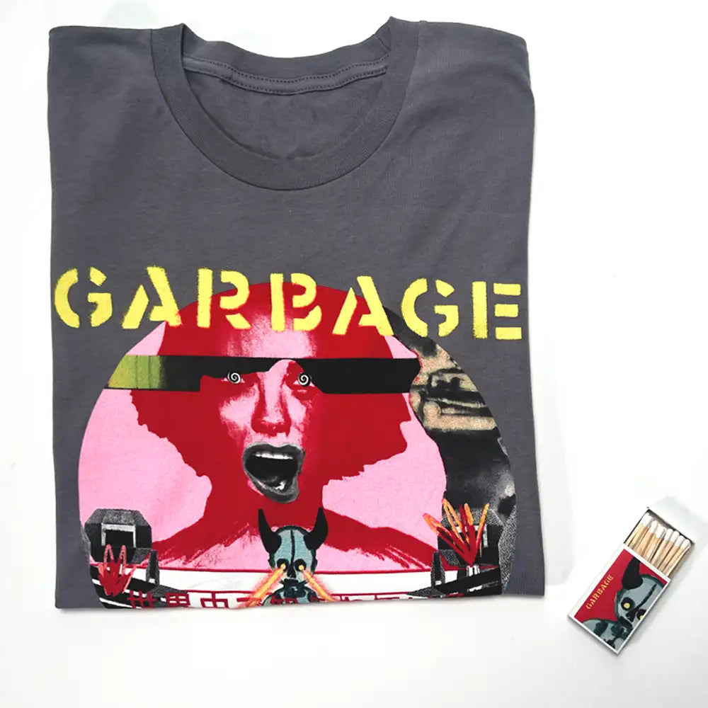 Grey t-shirt featuring a bold graphic of a screaming face with red and pink tones, black sunglasses, and the word ’garbage’ in yellow lettering across the chest.
