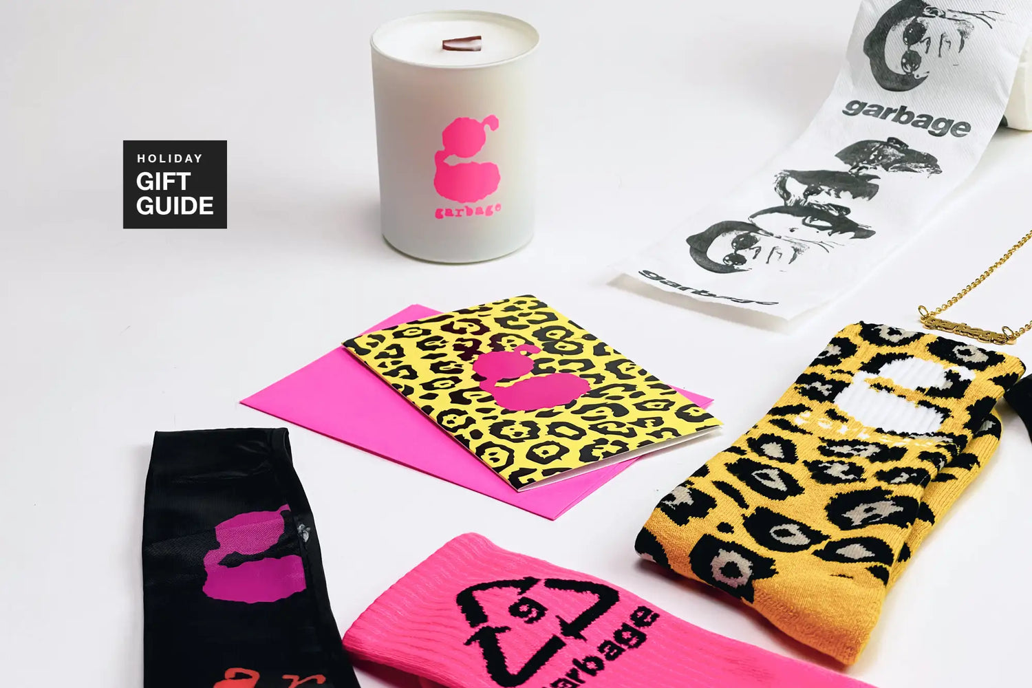 A white cylindrical candle with a pink garbage logo and two wooden wicks.